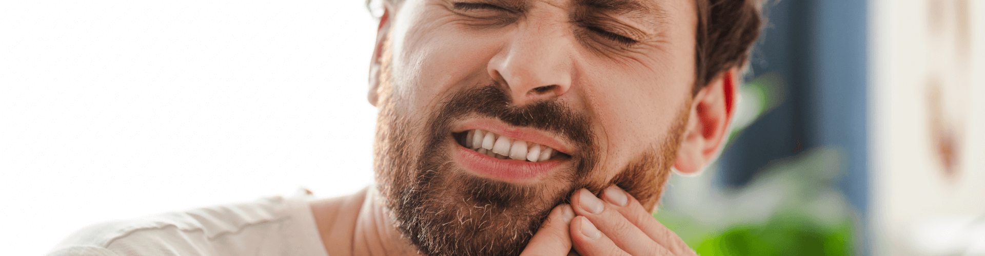 Man holding his cheek in pain.